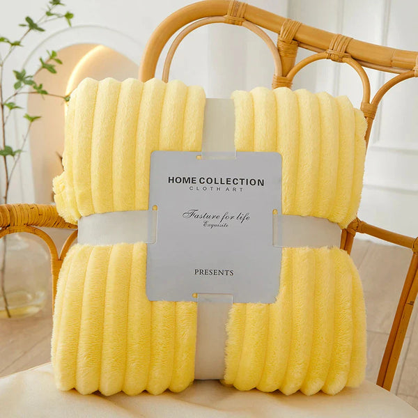 Gele fleece deken op rotan stoel, Home Collection label, zachte en warme textuur, perfect voor interieurdecoratie en comfort in de woonkamer.