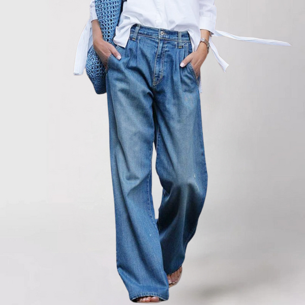 Wijdvallende damesjeans met hoge taille, gedragen met witte blouse en blauwe tas. Trendy casual mode, comfortabele pasvorm, denim stijl.