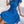 Vrouw in blauwe geplooide jurk met strik, zittend op bank. Elegante damesmode, zomerjurk, casual stijl. Perfect voor trendy outfits en mode-inspiratie.
