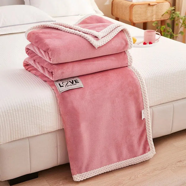 Roze fleece deken met witte rand, opgevouwen op bed, slaapkamerdecoratie, zachte en warme textielaccessoire, perfect voor interieurstyling.