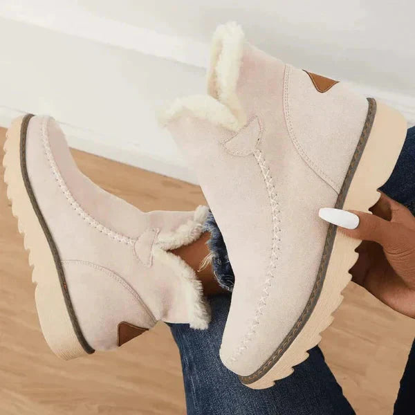 Beige suède enkellaarsjes met bontvoering, dikke rubberen zool en decoratieve stiksels. Perfect voor wintermode en casual outfits.