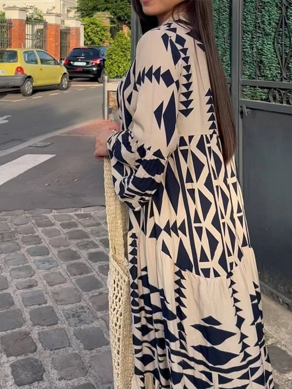 Vrouw in lange jurk met geometrisch zwart-wit patroon, staand op een geplaveide straat. Stijlvolle mode, zomerjurk, stedelijke achtergrond.