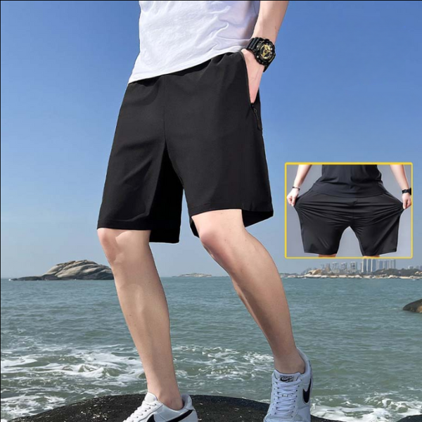 Man in zwarte sportshorts bij zee, met close-up van rekbare stof. Ideaal voor zomer, strand, sport. Comfortabele, ademende herenmode.