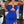 Vrouw in elegante blauwe jurk met halternek en hoge split, houdt een cocktailglas vast. Perfect voor zomerfeest of avondje uit.