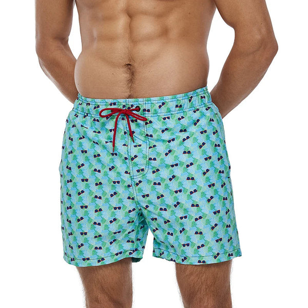Man in blauwe zwembroek met zonnebrillenprint en rode veter, strandmode, zomerkleding, herenzwembroek, casual zwemkleding.