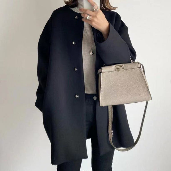 Vrouw in zwarte jas met beige handtas, draagt een grijze coltrui. Stijlvolle mode, herfstkleding, minimalistische accessoires, trendy outfit.