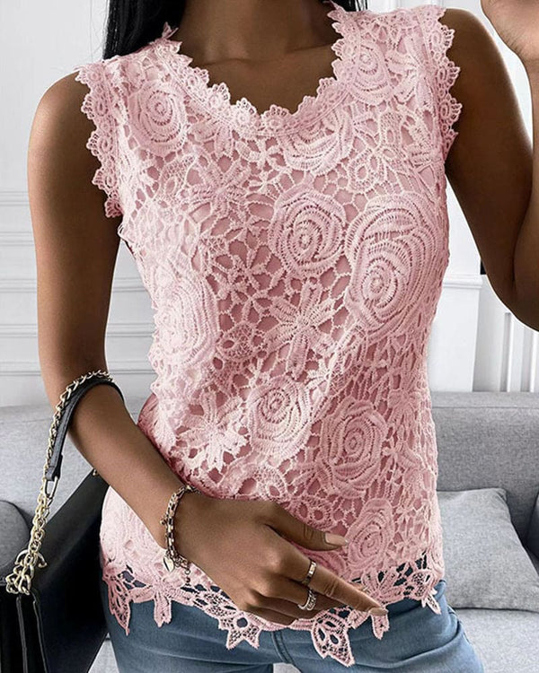 Vrouw draagt roze kanten top met bloemenpatroon, gecombineerd met blauwe jeans en zwarte handtas. Modieuze dameskleding, casual stijl.