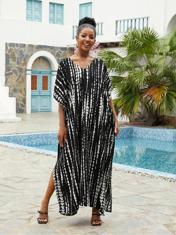 Vrouw in zwart-witte kaftan bij zwembad, tropische achtergrond, zomermode, vakantie, stijlvolle strandkleding, ontspannen sfeer.