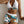 Vrouw in tropische sportset met haltertop en korte broek, wit en groen met bladerenprint. Perfect voor zomer, fitness en strandmode.