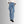 Vrouw draagt blauwe wijde jeans met hoge taille en zwarte laarzen, tegen een grijze achtergrond. Modieuze dameskleding, casual stijl.