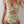 Vrouw in bloemenbadpak met ruches en uitsnijding, oranje en groene bloemenprint, zomermode, strandkleding, trendy damesbadmode.