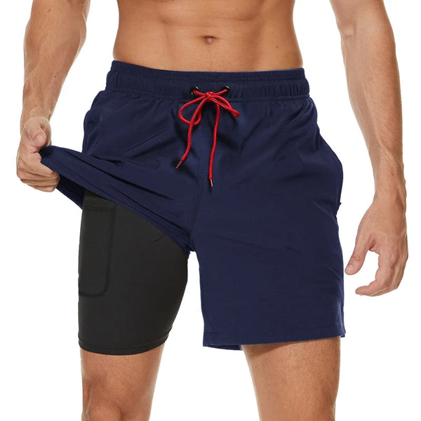 Man in sportshort met ingebouwde compressieshort, donkerblauw met rode trekkoord, geschikt voor fitness en hardlopen. Comfortabele en functionele sportkleding.