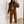 Vrouw in bruine joggingpak met crop top, houdt beige handtas vast, maakt selfie in moderne kamer. Trendy damesmode, comfortabele loungewear.