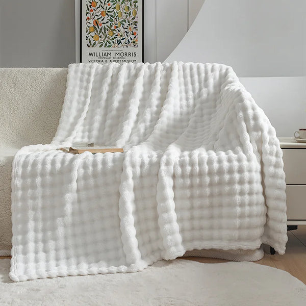 Witte, geruite fleece deken op een bank in een moderne woonkamer, naast een kunstposter van William Morris. Comfortabel en stijlvol interieur.