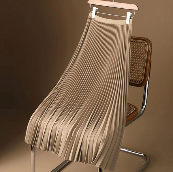 Beige geplooide rok op houten hanger, geplaatst op retro stoel. Modieuze dameskleding, elegant design, perfect voor casual en formele gelegenheden.