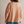 Vrouw in gestreepte trui met oranje en witte strepen, blauwe boorden, en lichtblauwe korte broek. Modieuze dameskleding, casual stijl.