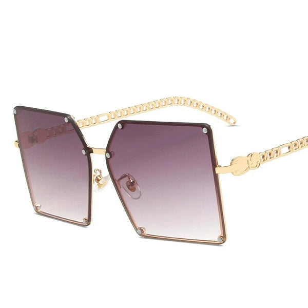 Gouden oversized zonnebril met vierkante glazen en kettingpootjes, modieuze damesaccessoire, UV-bescherming, trendy design.
