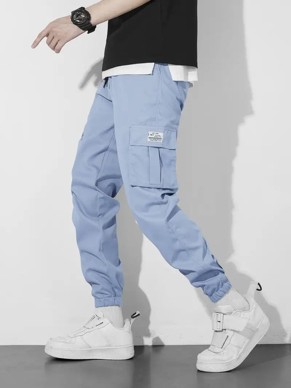 Man in blauwe cargobroek en witte sneakers, zijaanzicht. Modieuze streetwear, casual stijl, comfortabele pasvorm, geschikt voor dagelijks gebruik.