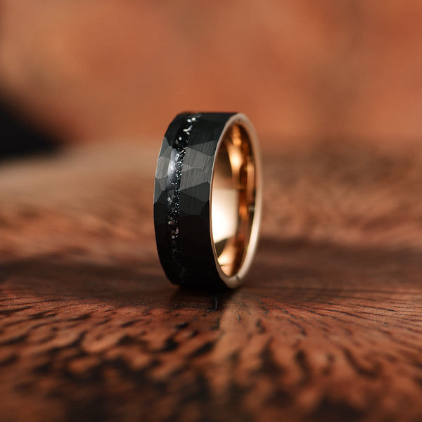 Zwart titanium herenring met facetten en gouden binnenkant, op houten achtergrond. Stijlvolle trouwring, modern design, duurzame sieraden.