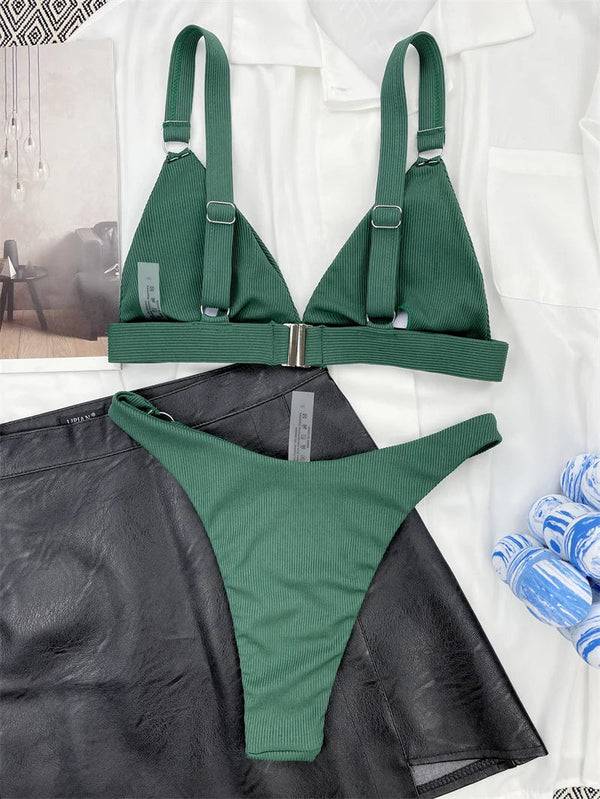 Groene ribgebreide bikini set met verstelbare bandjes en metalen sluiting, gestyled op een zwarte leren rok en witte blouse. Perfect voor zomertrends.