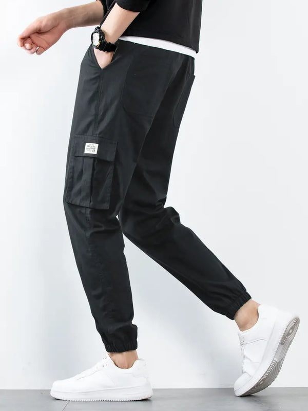 Man in zwarte cargo broek en witte sneakers, zijaanzicht. Stijlvolle streetwear mode, comfortabele pasvorm, geschikt voor casual en urban outfits.