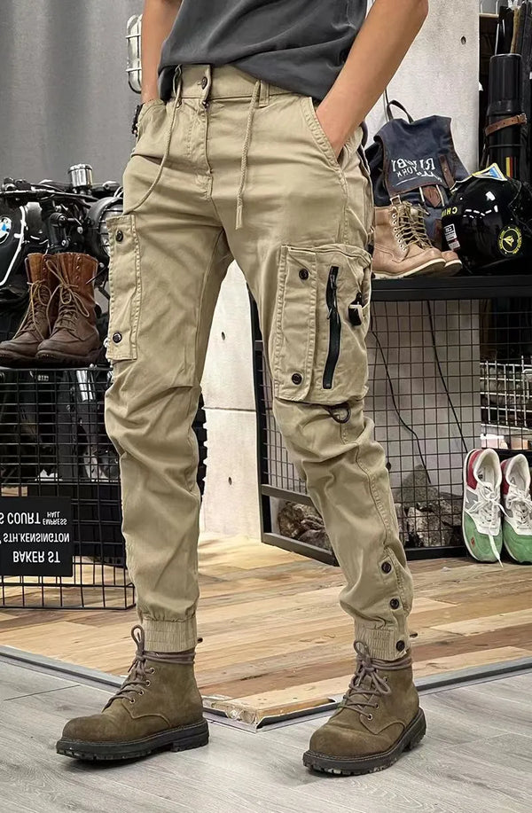 Beige cargobroek met meerdere zakken en zwarte ritsen, gedragen met bruine laarzen. Ideaal voor outdoor activiteiten en casual mode.