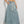 Vrouw in denim maxi rok met elastische tailleband en witte trekkoorden, gecombineerd met een crop top en sneakers. Trendy casual damesmode.