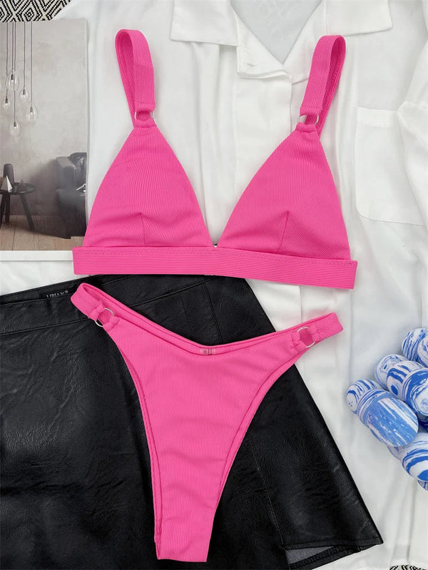Roze ribgebreide bikini set met triangel top en hoge taille slip, gestyled op zwarte leren rok en witte blouse. Perfect voor strandmode.