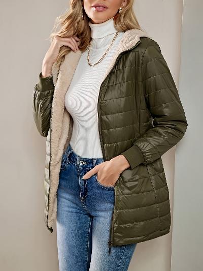 Vrouw in groene gewatteerde jas met capuchon, witte coltrui en blauwe jeans. Modieuze winterkleding, casual stijl, damesmode.