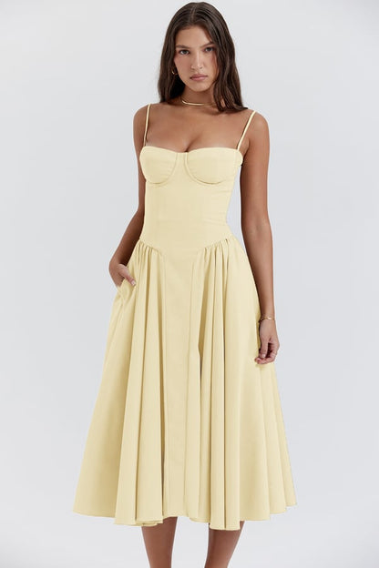 Vrouw in elegante gele midi-jurk met spaghettibandjes en geplooide rok, perfect voor zomermode en casual chique gelegenheden.