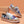 Floral damessneakers met kurkdetails en witte zolen, geplaatst op een houten kist tegen een perzikkleurige achtergrond. Trendy en duurzaam schoeisel.