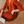 Vrouw in stijlvolle oranje gebreide jurk en vest, zittend op houten stoel, met tijdschrift. Mode, herfstkleding, elegantie, binnenhuis.