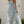 Vrouw in lichtblauwe zomerjurk met halternek, staand voor witte deur. Elegante mode, casual stijl, zomerkleding.