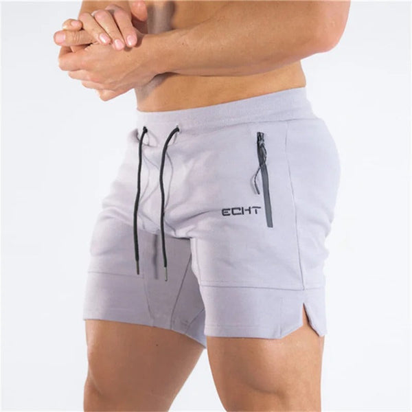 Man in grijze sportshorts met trekkoorden en zakken, merklogo zichtbaar. Ideaal voor fitness en hardlopen. Comfortabele en stijlvolle sportkleding.