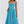 Vrouw in elegante blauwe midi-jurk met spaghettibandjes en geplooide rok, perfect voor zomermode en casual chique gelegenheden.
