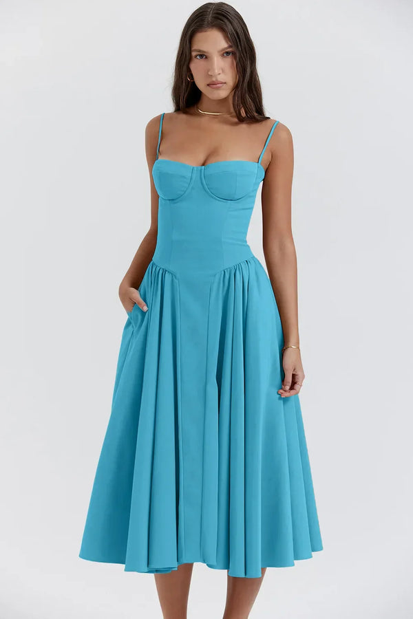 Vrouw in elegante blauwe midi-jurk met spaghettibandjes en geplooide rok, perfect voor zomermode en casual chique gelegenheden.
