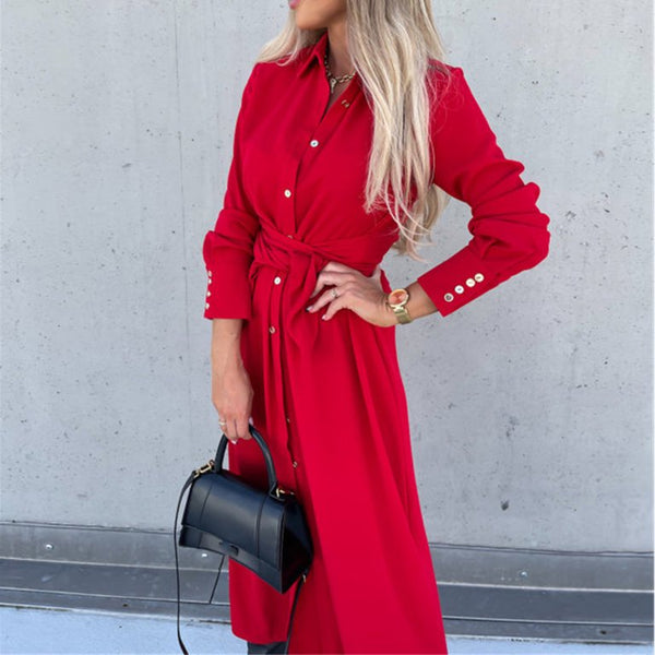Vrouw in rode jurk met knoopsluiting en zwarte handtas, tegen een grijze achtergrond. Modieuze dameskleding, elegante stijl, trendy accessoires.