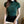 Vrouw in groene coltrui en zwarte rok, draagt een zilveren ketting en horloge. Stijlvolle damesmode, casual chique outfit, moderne kledingstijl.