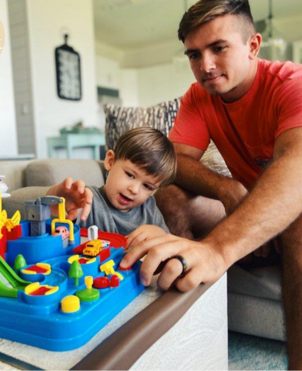 Vader en zoon spelen met kleurrijk educatief speelgoed op tafel in woonkamer. Interactief kinderspeelgoed, ouder-kind interactie, gezinsactiviteit.