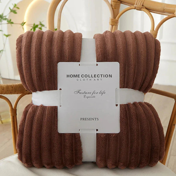 Bruine geribbelde fleece deken op rotan stoel, Home Collection Clothart, luxe en zachte textuur, perfect voor interieurdecoratie en comfort.