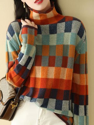 Vrouw in kleurrijke geruite trui met hoge kraag, oranje, blauw en groen tinten, draagt een bruine schoudertas. Modieuze herfstkleding.