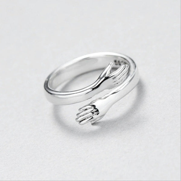 Zilveren ring met uniek ontwerp van omarmende handen, minimalistisch en elegant, perfect als cadeau of accessoire voor dagelijks gebruik.