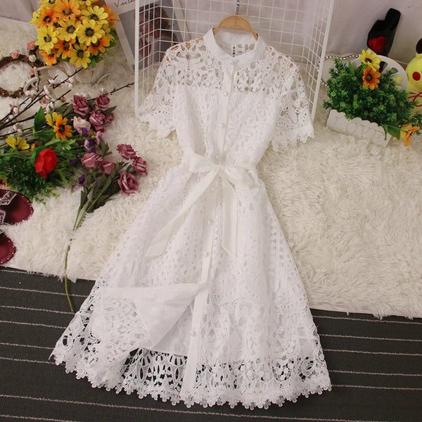 Witte kanten jurk met korte mouwen en strikceintuur, elegant ontwerp, geschikt voor zomerbruiloften en feestjes, op een decoratieve achtergrond.