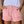 Vrouw draagt roze katoenen shorts met ruches en elastische tailleband, gecombineerd met een lichtblauw T-shirt. Zomermode, casual dameskleding.
