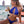 Vrouw in blauwe bikini drinkt cocktail op strand, met zee en lantaarns op achtergrond. Zomerse strandmode, vakantie, tropische sfeer.