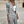 Grijze gestreepte damespak met cropped blazer en hoge taille broek, gedragen met een witte crop top. Stijlvolle zakelijke mode voor vrouwen.