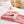Roze fleece deken met witte rand op bed, luxe label zichtbaar. Perfect voor slaapkamerdecoratie, comfort en warmte. Ideaal voor moderne interieurs.