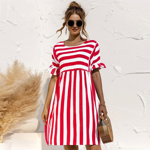 Vrouw in rood-wit gestreepte jurk met korte mouwen, zonnebril en rieten tas. Zomermode, casual dameskleding, strandstijl.