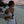 Vrouw in elegante witte jurk op tropisch strand bij zonsondergang, met palmbomen en gedekte tafels op de achtergrond. Perfect voor strandvakantie.