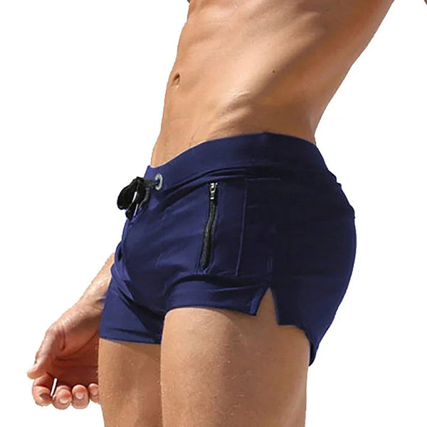 Man in donkerblauwe zwembroek met ritszakken, strandmode voor heren, sportieve zwemkleding, zomerse outfit, strakke pasvorm.